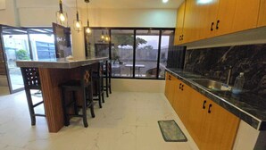 A modern kitchen with a marble countertop, wooden cabinets, and a bar area with stools. - SC RESORT (Concepcion)