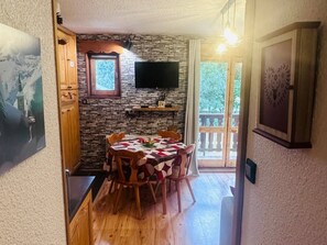 A dining area with a stone wall, wooden table, and chairs. - Studio cabin 4 pers, balcony, Valloire (Valloire)