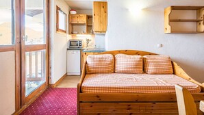 A compact room with a bed, a kitchenette, and a large window. - Charming apartment for 4 with mezzanine, near slopes in Plagne Villages (Plagne Villages)