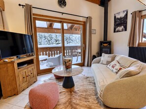 Ein gemütliches Wohnzimmer mit Fernseher, Glastisch, Sofa und Kamin.