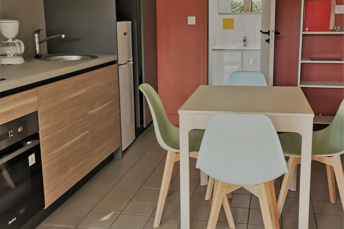 A modern kitchen with a sink, stove, and refrigerator. There is a dining area with a table and chairs.