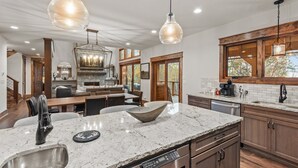 A spacious kitchen with granite countertops, a built-in dishwasher, and a large island with a bowl.