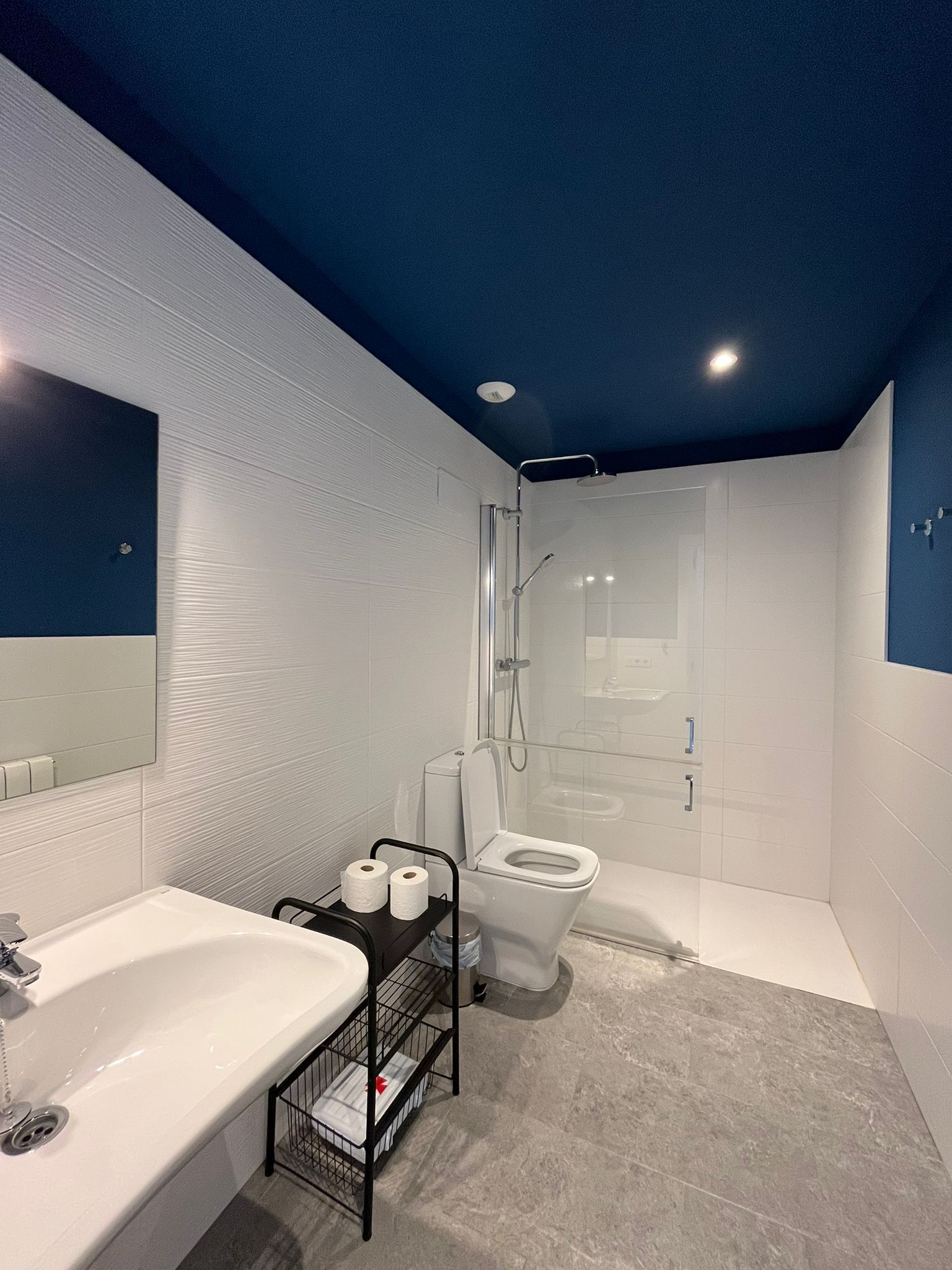 A modern bathroom with a white sink, toilet, and shower.