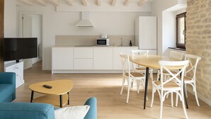 A modern living room with a TV, sofa, and coffee table. There is a kitchen area with a microwave and cabinets. - Otero de Campoo (Hermandad de Campoo de Suso)
