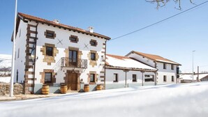 A traditional white building with brown accents, a wooden door, and a balcony with a metal railing. - Otero de Campoo (Hermandad de Campoo de Suso)