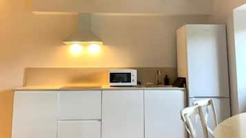 A compact kitchen with white cabinets, a microwave, and a refrigerator.
