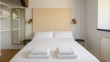 A modern bedroom with a large bed, wooden headboard, bedside tables, and a built-in wardrobe.