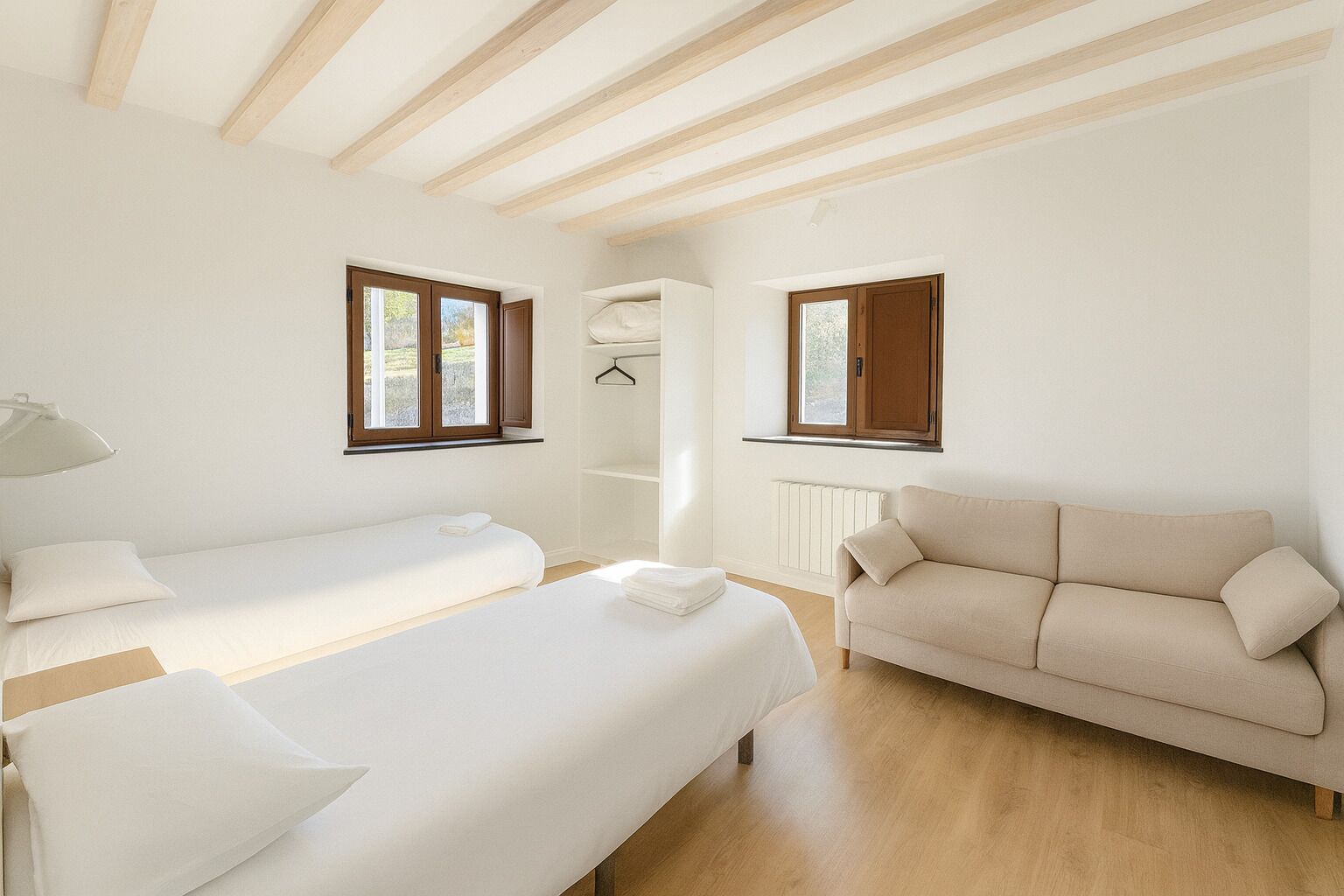 Une chambre avec deux lits, un canapé, un radiateur et deux fenêtres.