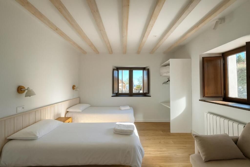 Un dormitorio con dos camas, una ventana y techo de madera.