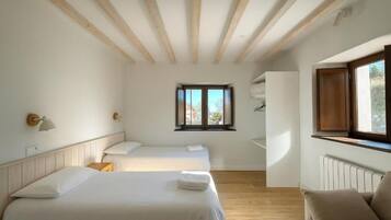 Un dormitorio con dos camas, una ventana y techo de madera.