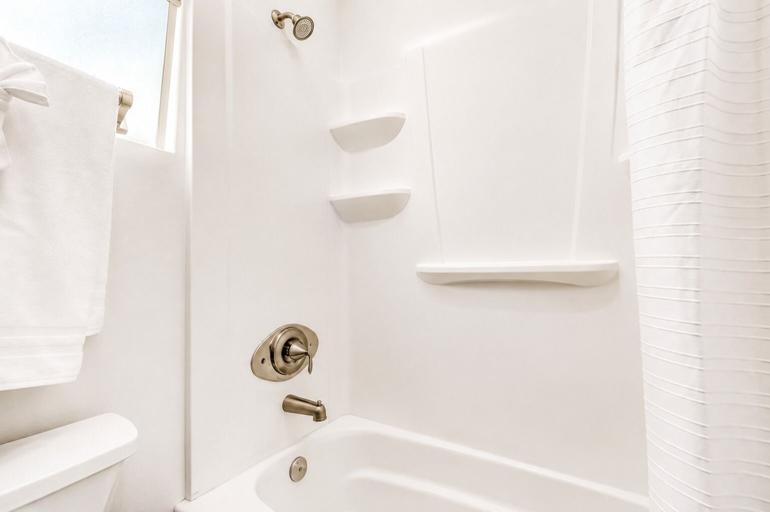 A bathroom with a bathtub, a toilet, and a shower area.