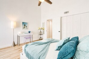 A bedroom with a bed, a desk, a chair, a lamp, and a door. - Lux Beach Cabana - Close to Beach & Restaurants (St. Augustine)