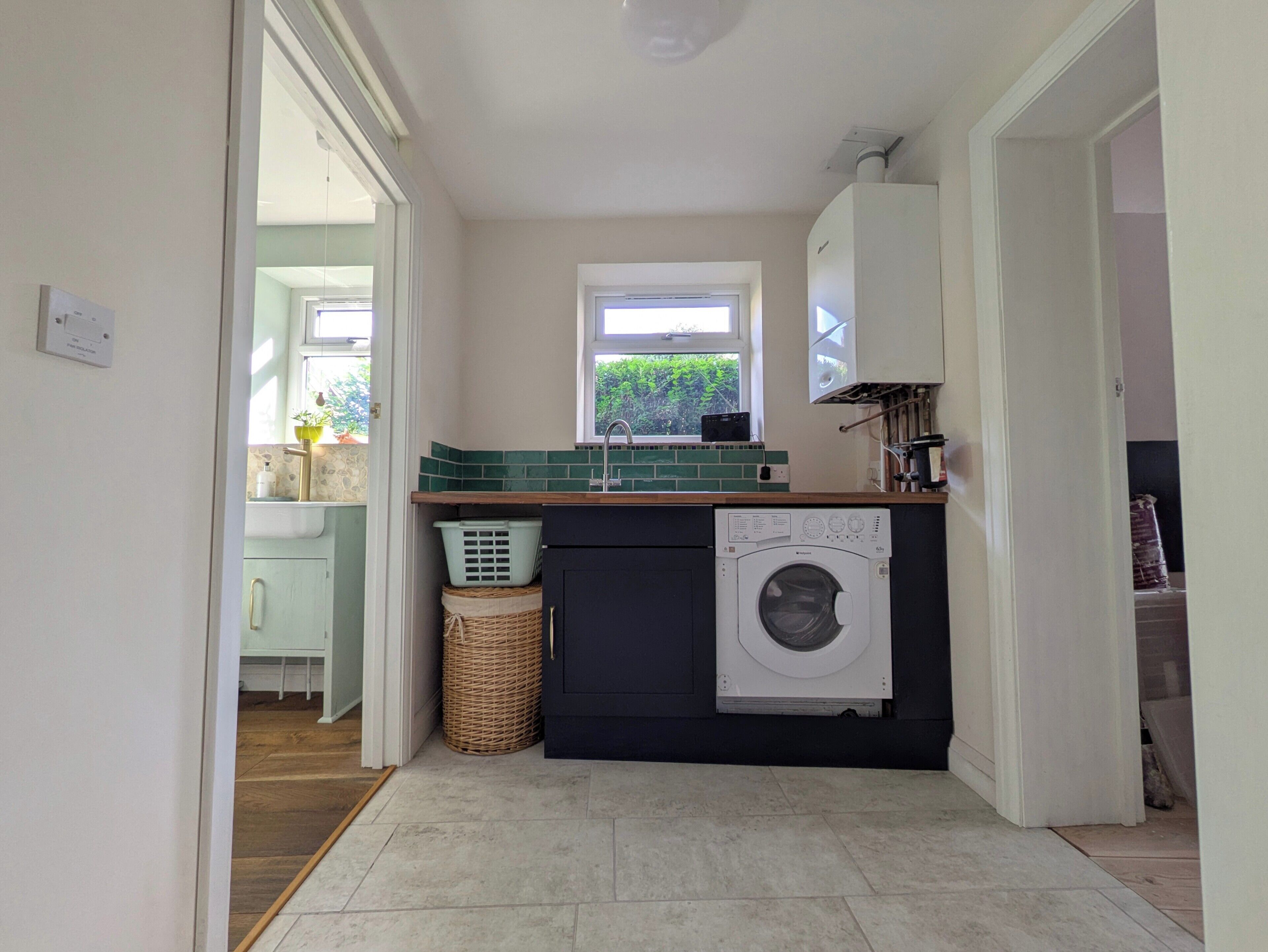 A compact kitchen with a washing machine, a window, and a small sink.