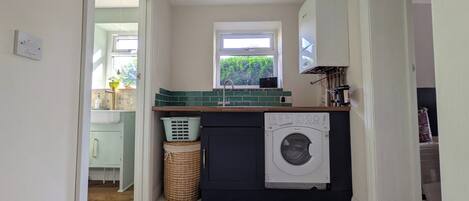 A compact kitchen with a washing machine, a window, and a small sink.