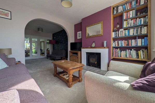 A living room with a fireplace, a bookshelf, and a television. - Cherry View House 3 Bed Garden Parking Sleeps 8 (Bristol)