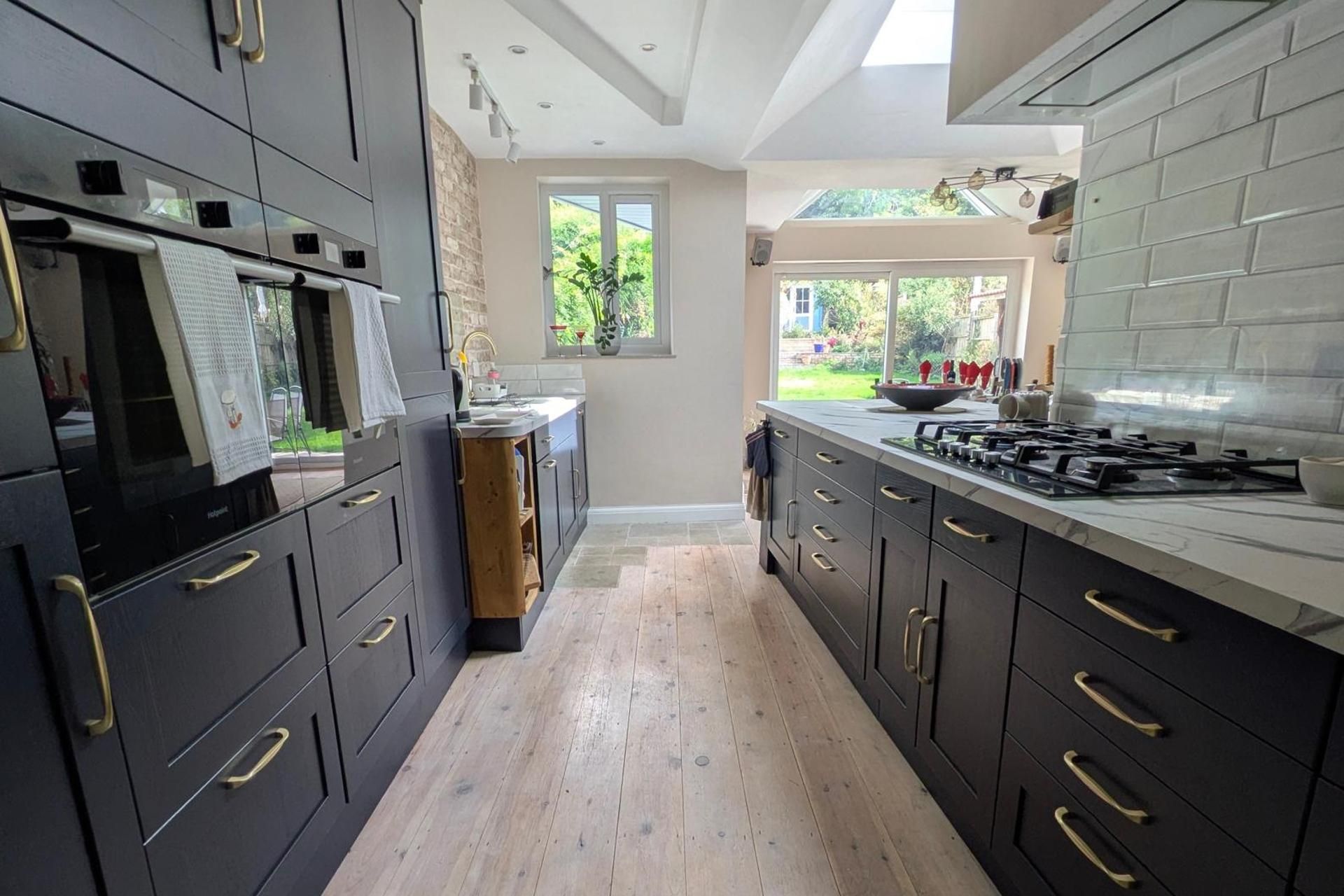 Una cocina moderna con armarios oscuros, una isla central y vistas al exterior.