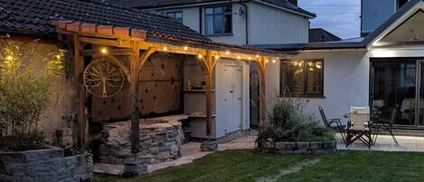 A covered outdoor area with stone walls, a wooden structure, and string lights.