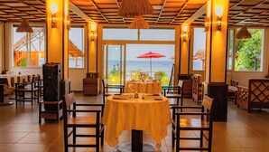 Un restaurante con vista al mar, con mesas y sillas de madera y amplios ventanales.