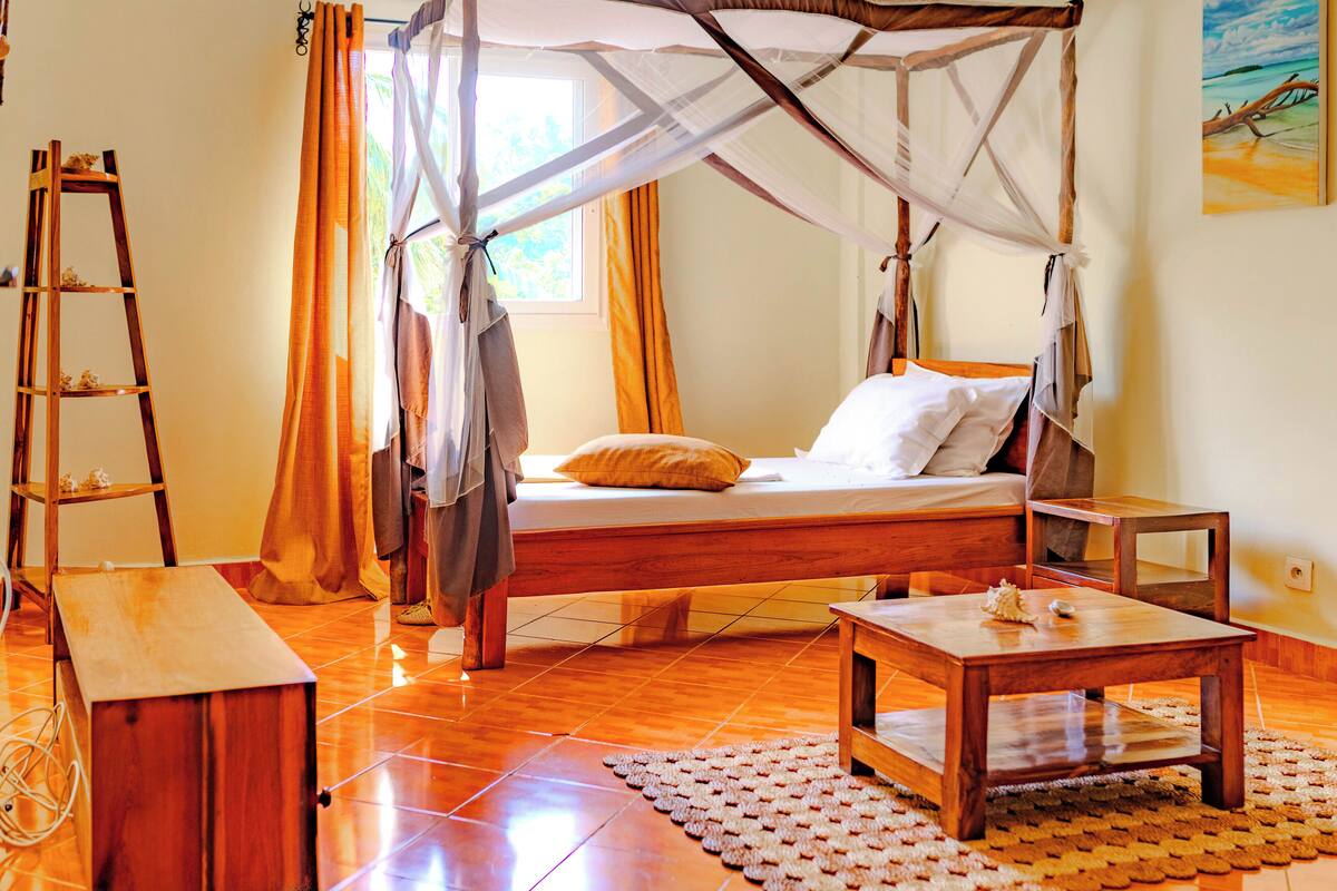 A bedroom with a wooden bed, a wooden nightstand, a wooden bench, and a wooden ladder.