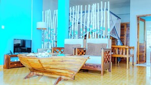 Una habitación con una mesa de centro en forma de barco de madera, una cama con dosel, un televisor y una silla de madera.