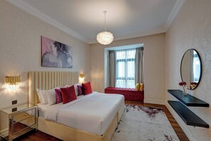 Een moderne slaapkamer met een groot bed, een nachtkastje, gordijnen voor het raam, een hanglamp, een schilderij, een spiegel en een houten vloer.