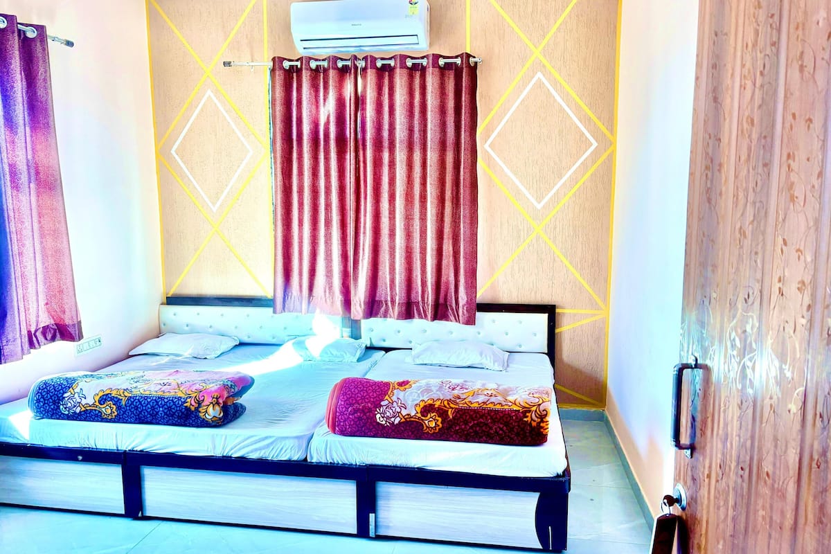 A bed with a headboard, a wall-mounted air conditioner, and geometric-patterned curtains.