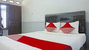 A bedroom with a bed, a wooden door, and a window. - OYO 90369 Syariah An Nur (Cigombong)