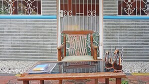 A wooden chair with a cushion and a small table with a notebook and a pen. - OYO 90369 Syariah An Nur (Cigombong)
