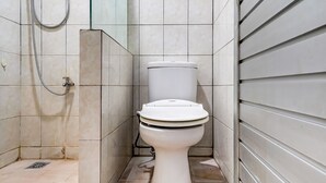 A bathroom with a toilet, shower, and tiled walls. - OYO 90369 Syariah An Nur (Cigombong)