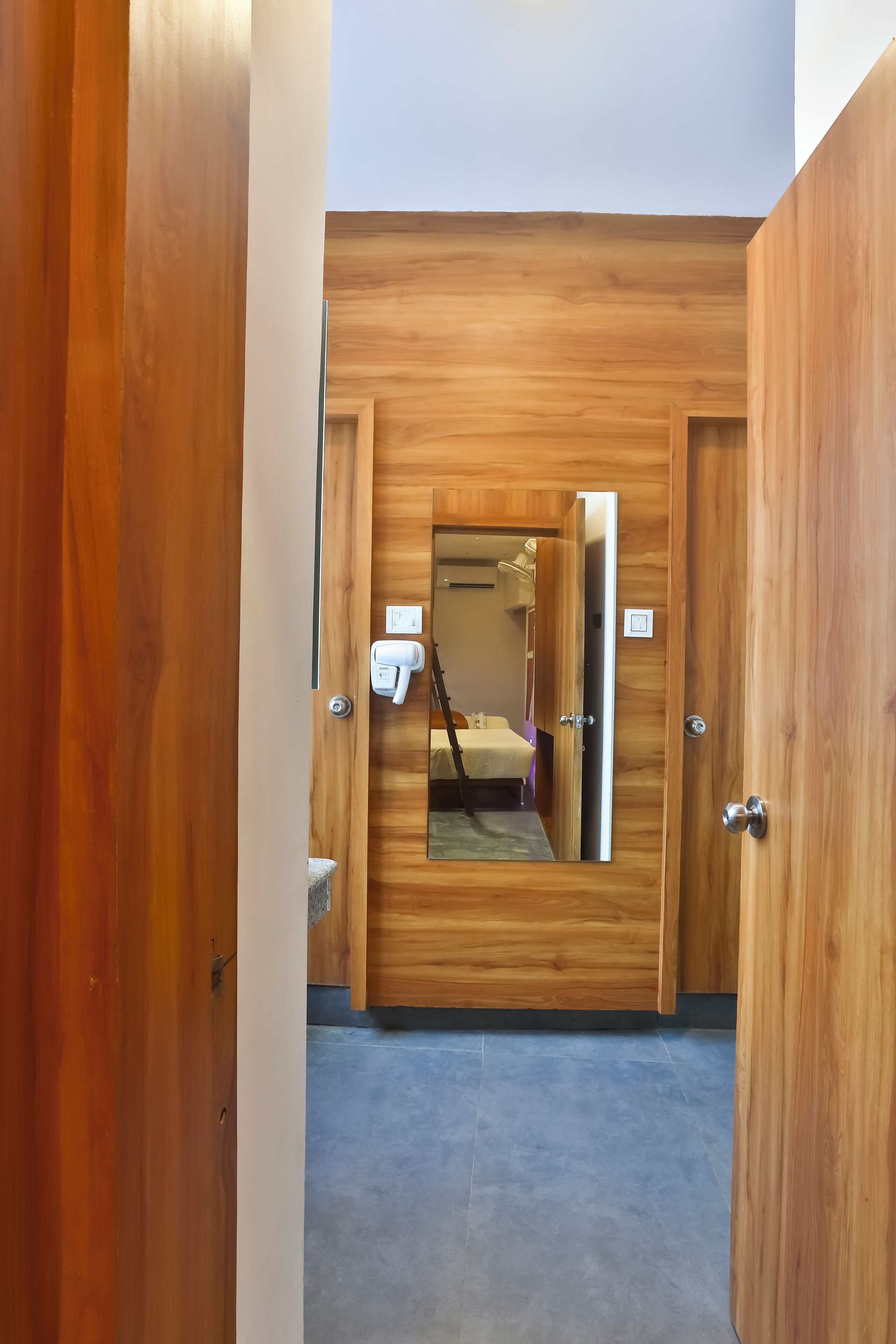 Une porte en bois avec un miroir, un sèche-cheveux et un lit visible à travers la porte.