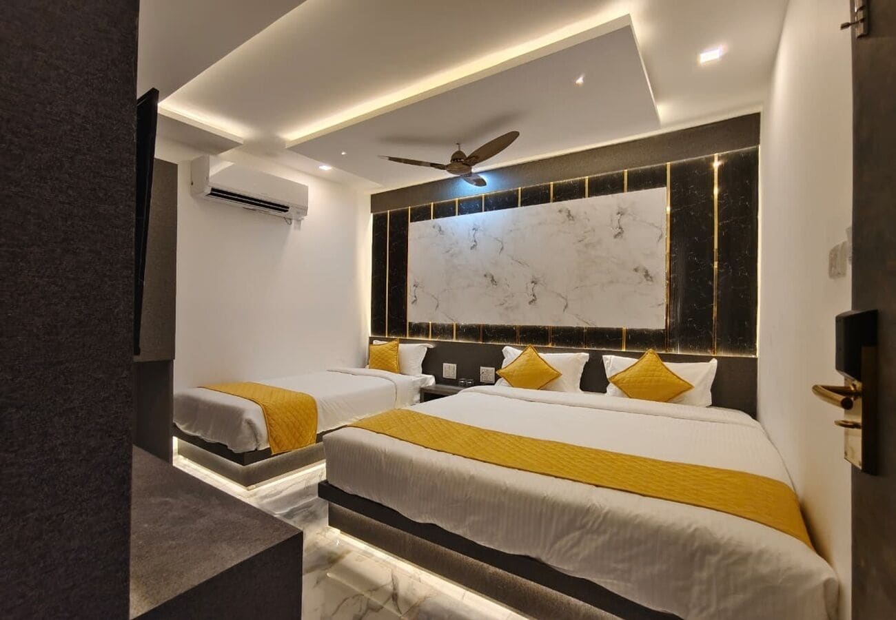 Une chambre d’hôtel avec deux lits, un ventilateur de plafond et un mur décoratif en marbre.