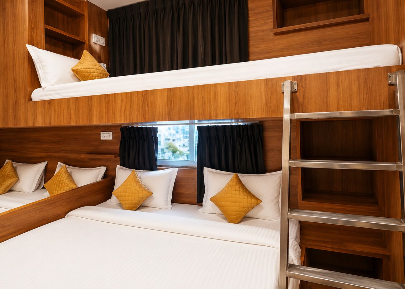 A bunk bed with white bedding and gold pillows, wooden paneling, and a window with curtains.