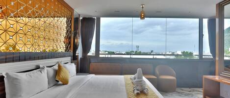 A hotel room with a large bed, a view of the city, and a balcony with seating.