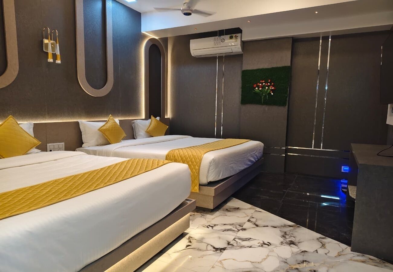 Ein Hotelzimmer mit zwei Betten, einem Marmorboden, einer Klimaanlage und einem kleinen Schreibtisch.