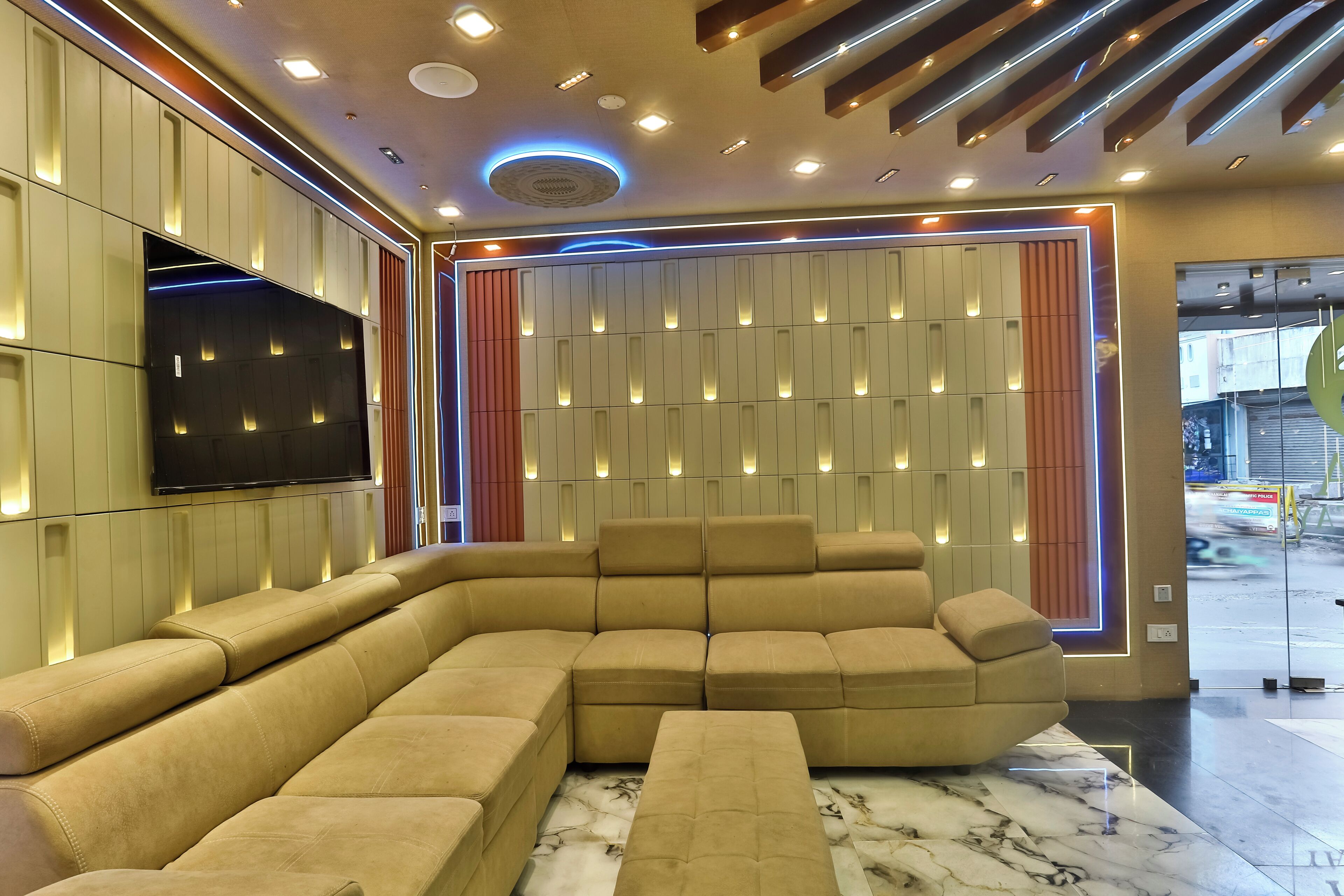 Een modern interieur met een hoekbank, inbouwverlichting en een flatscreen televisie aan de muur.