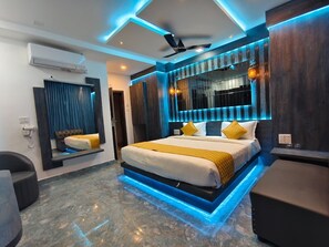 A modern bedroom with a bed, a ceiling fan, and a built-in TV. - Sara Happy Stay (Tiruvannamalai)