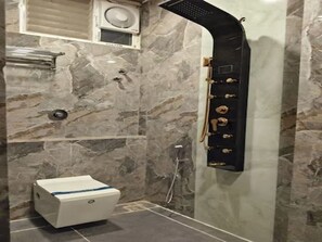 Baño con pared de mármol, inodoro y cabina de ducha.