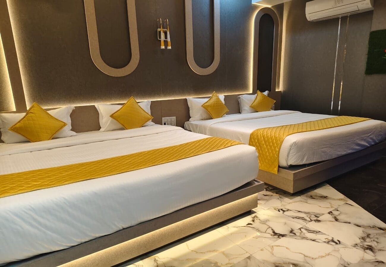 Habitación de hotel con dos camas, cada una con cabecero, y suelo de mármol.