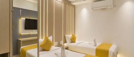 A hotel room with two beds, a ceiling fan, an air conditioning unit, and a television.