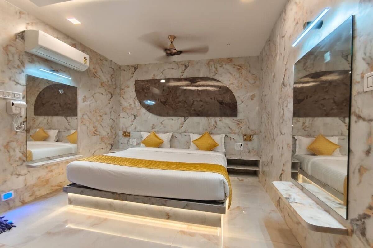 A modern bedroom with a bed, air conditioning unit, ceiling fan, and marble walls.