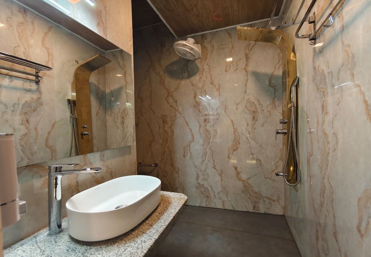 A modern bathroom with a freestanding bathtub, a showerhead, and marble walls.