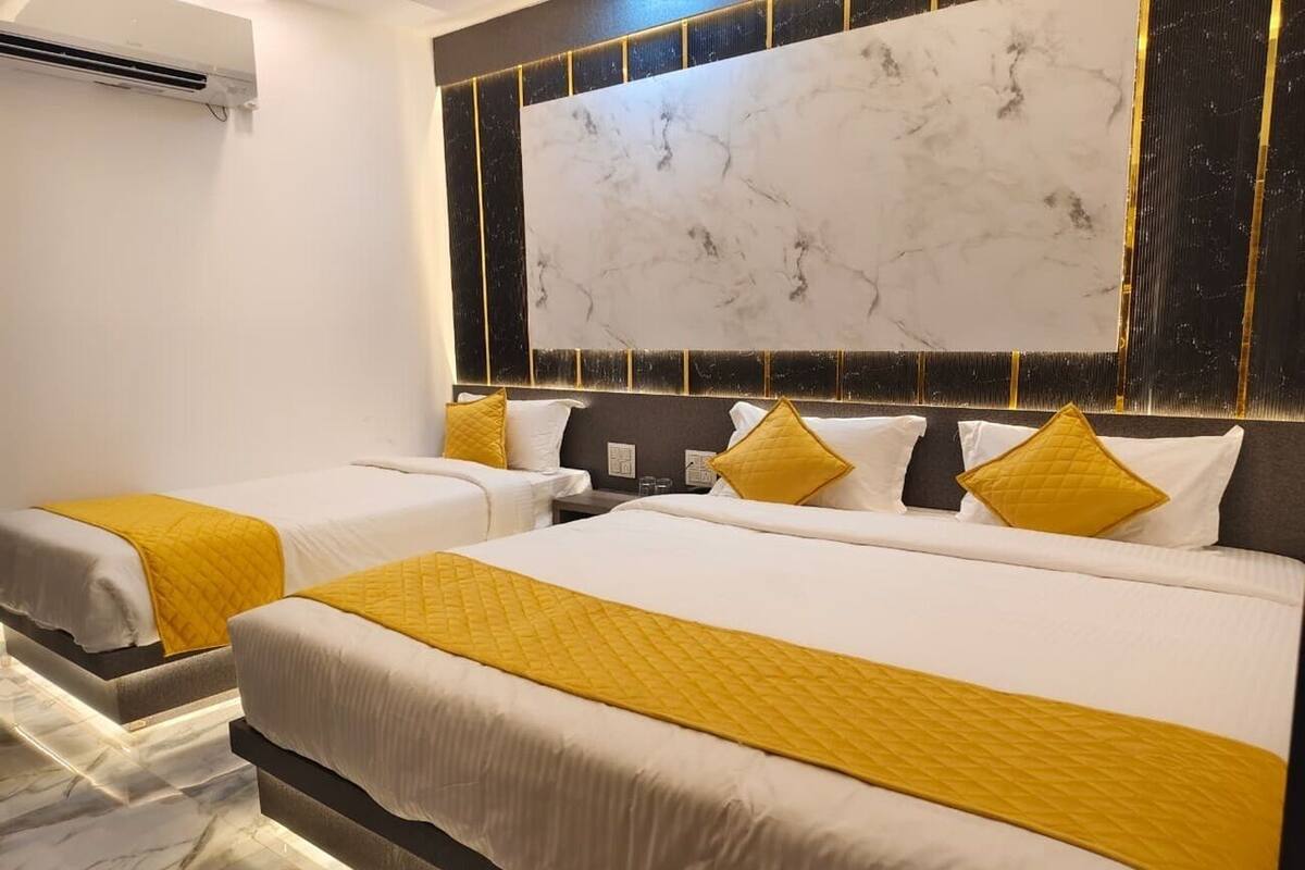 A hotel room with two beds, marble flooring, and a large marble wall.