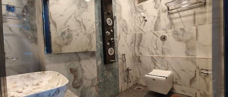 Een badkamer met een marmeren wastafel, een douche met regendouche, een toilet en een houten bankje.