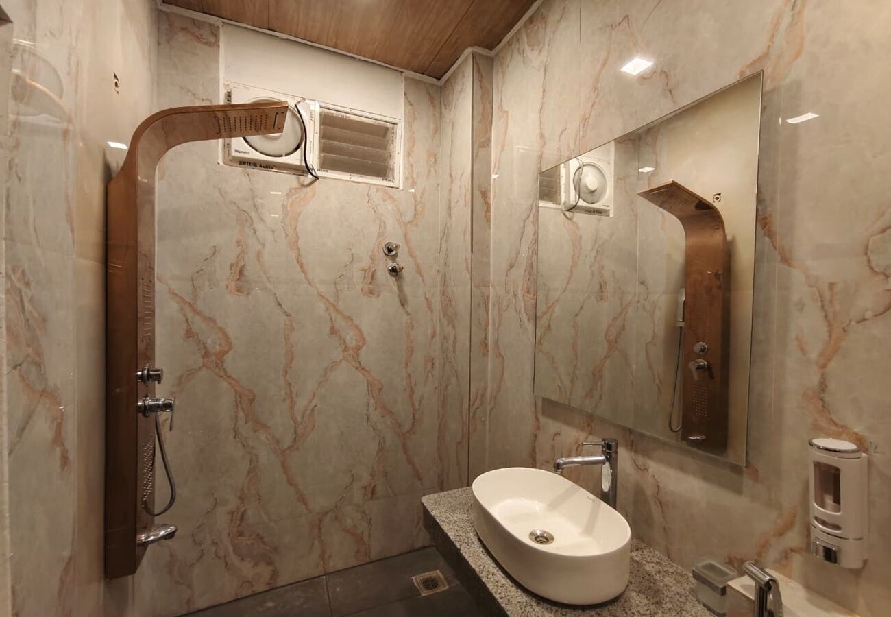 Une salle de bain avec un mur en marbre, un lavabo, une douche et un miroir.