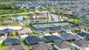 Een woonwijk met huizen, een tennisbaan en een klein meer.