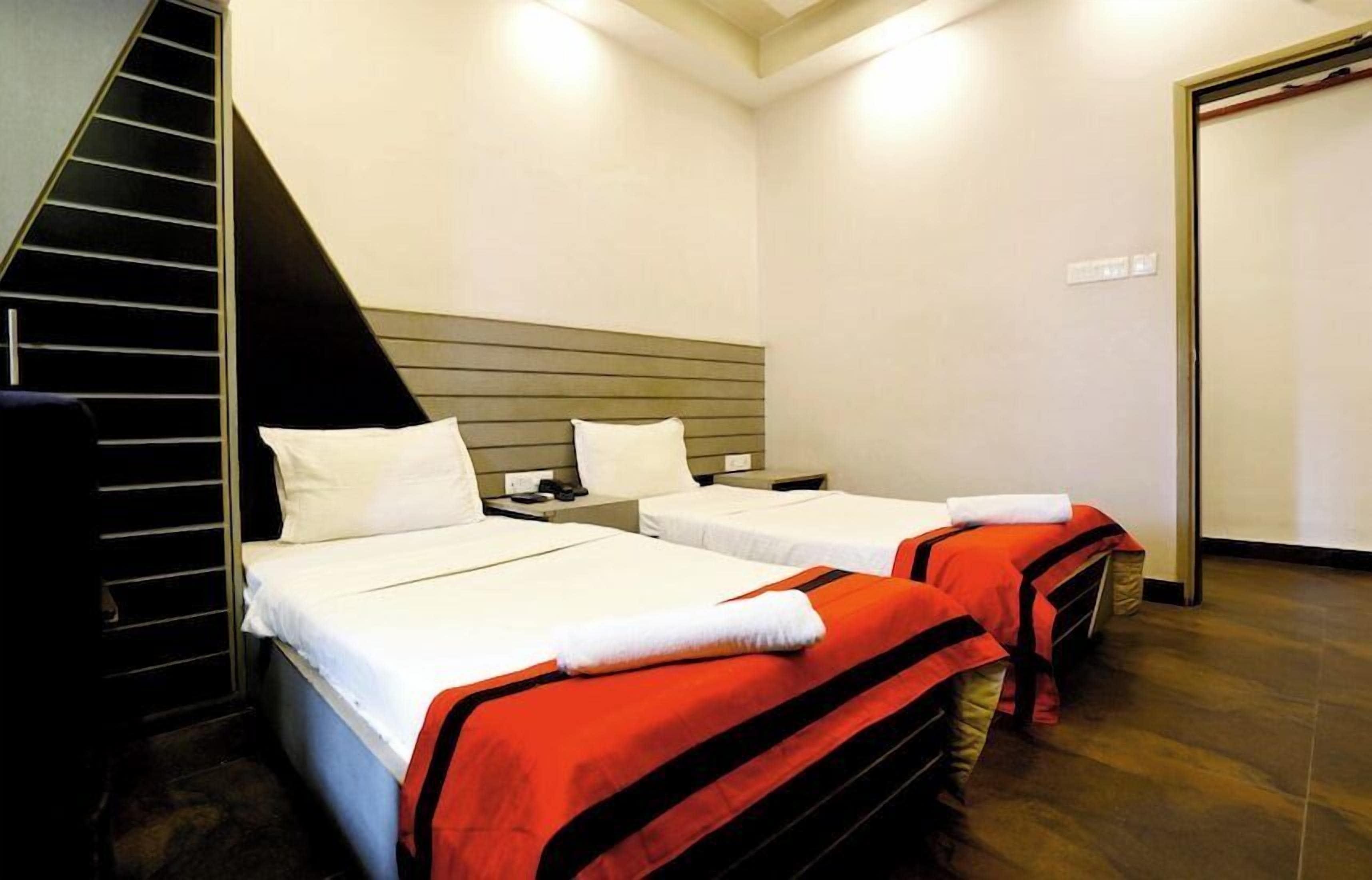 A hotel room with two beds, a staircase, and a door.