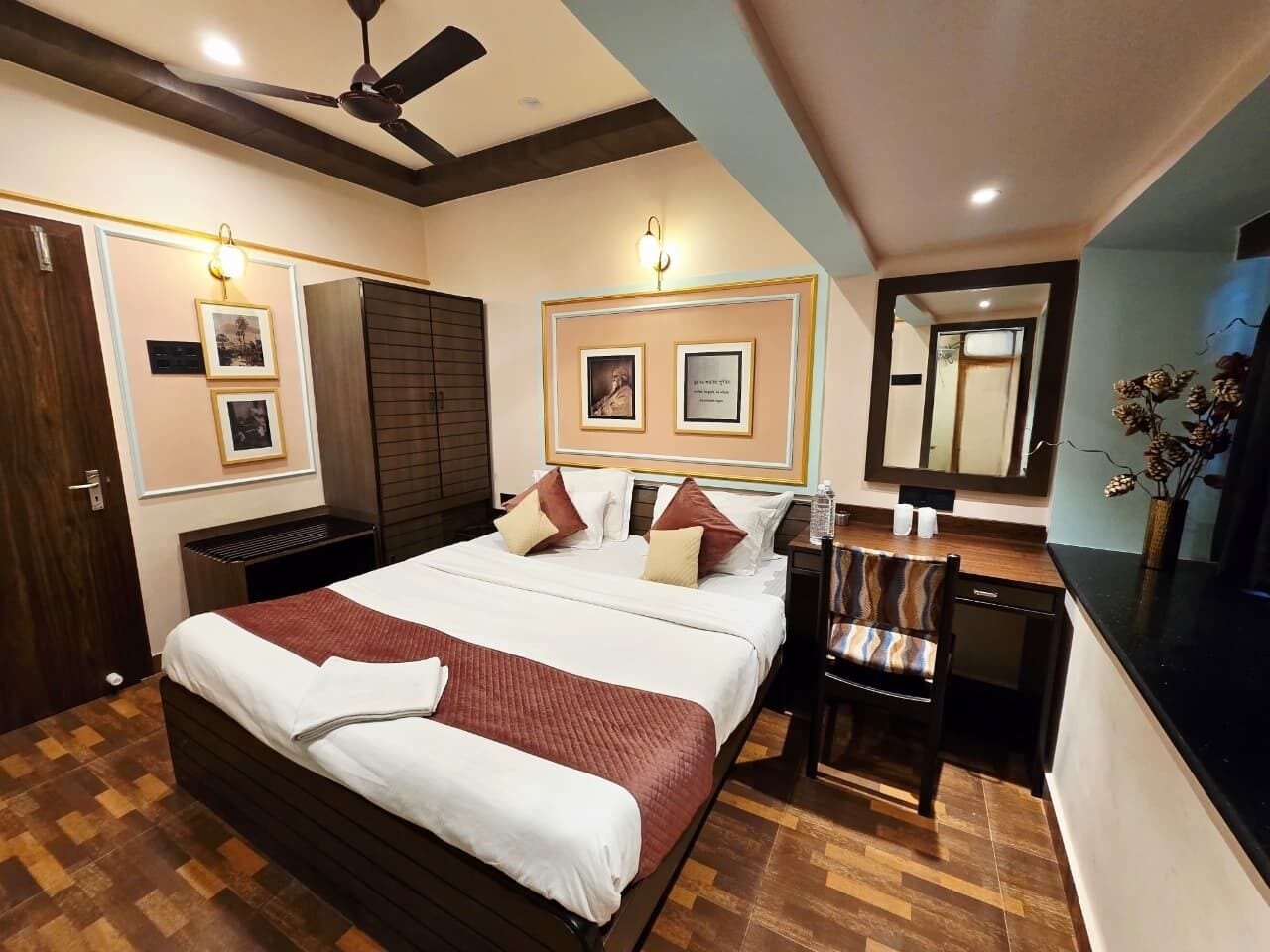Una habitación de hotel con cama, mesita de noche, silla y escritorio con espejo.