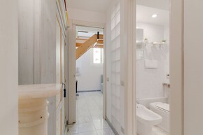 A hallway leading to a bathroom with a bathtub, toilet, and shower.