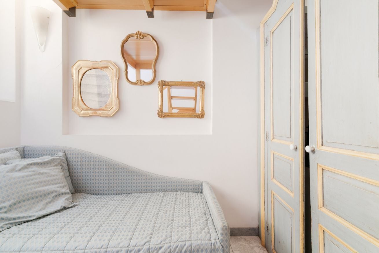 Une chambre à coucher comprenant un lit, une armoire et trois miroirs fixés au mur.