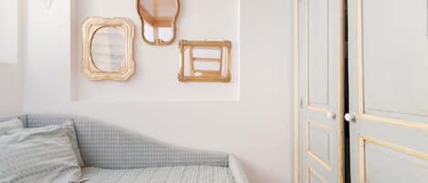 Un dormitorio con una cama, un armario y tres espejos adosados a la pared.